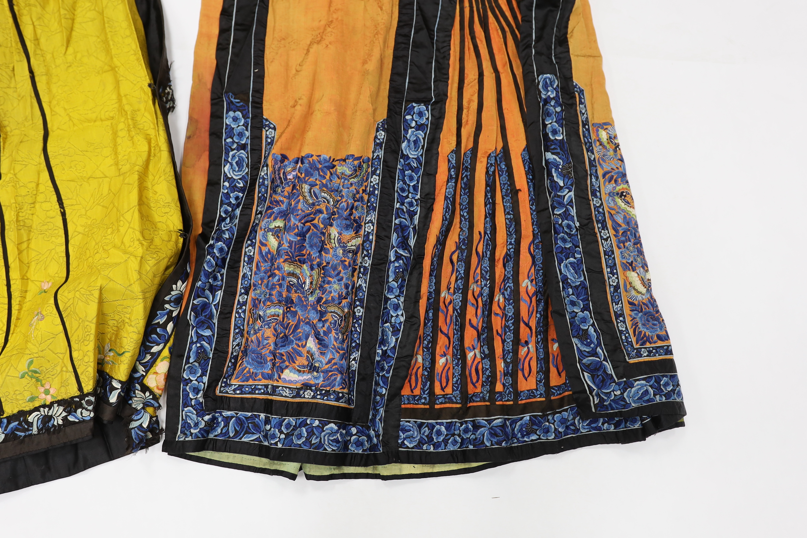 A late Chinese Qing yellow silk damask wedding skirt, with polychrome coloured silk embroidery, together with a similar coral silk damask blue embroidered wedding skirt